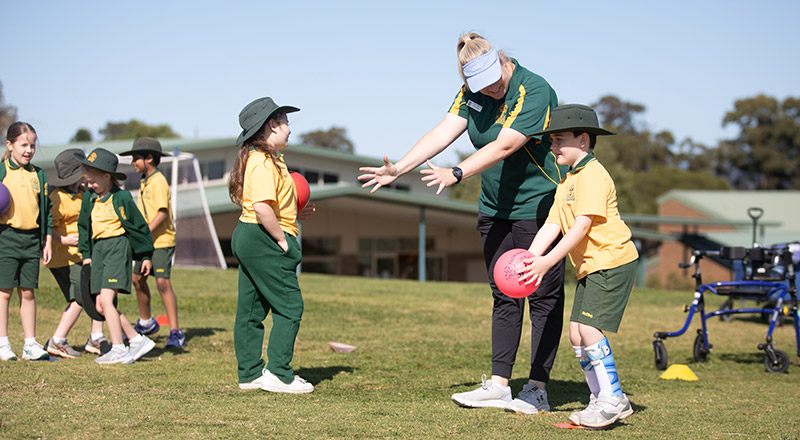 Teacher playing sports with her students on the school oval at St Mary MacKillop Primary School South Penrith
