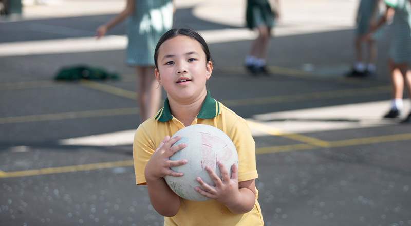 Student holding a ball in the playground at St Mary MacKillop Primary School South Penrith
