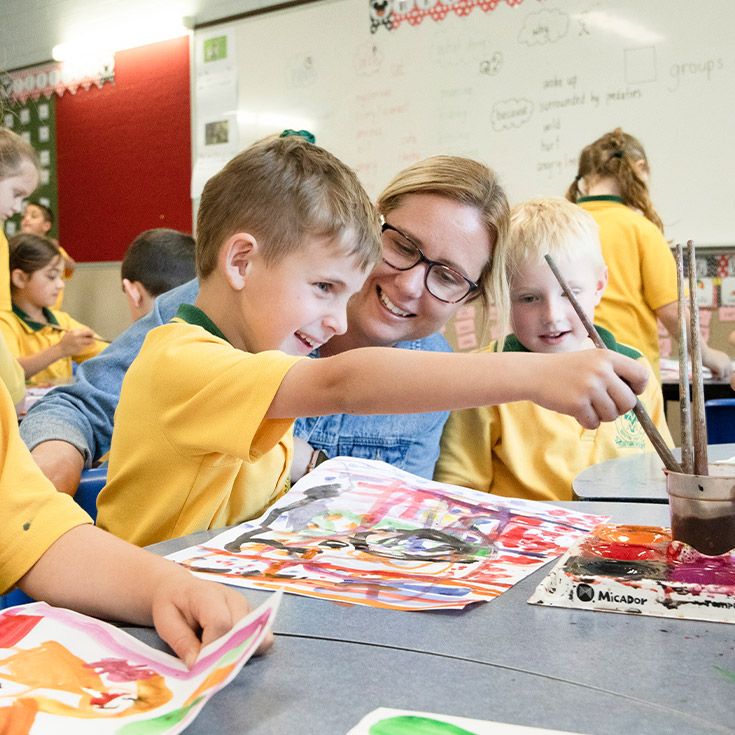 Teacher painting with her student in the classroom at St Mary MacKillop Primary School South Penrith
