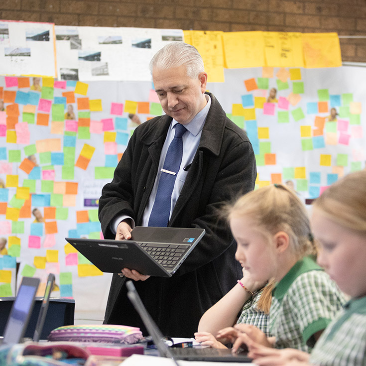 Teacher helping his students in the classroom at St Mary MacKillop Primary School South Penrith