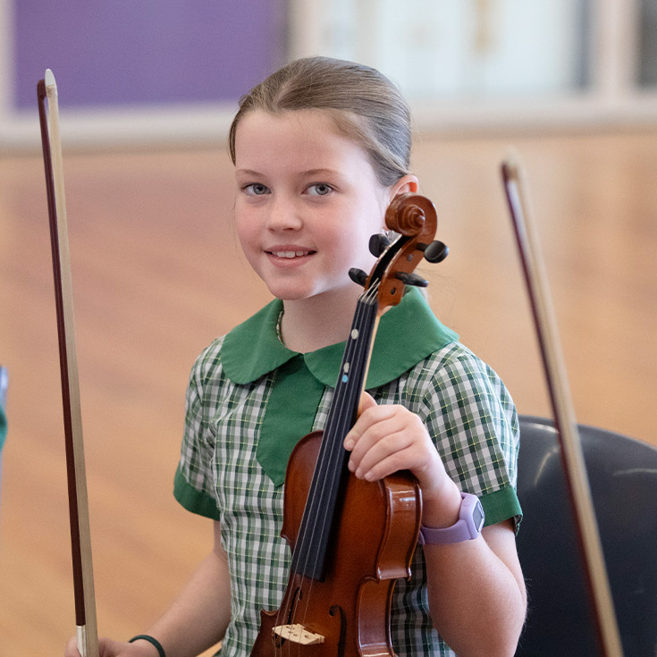 Student learning to play violin in the classroom at St Mary MacKillop Primary School South Penrith