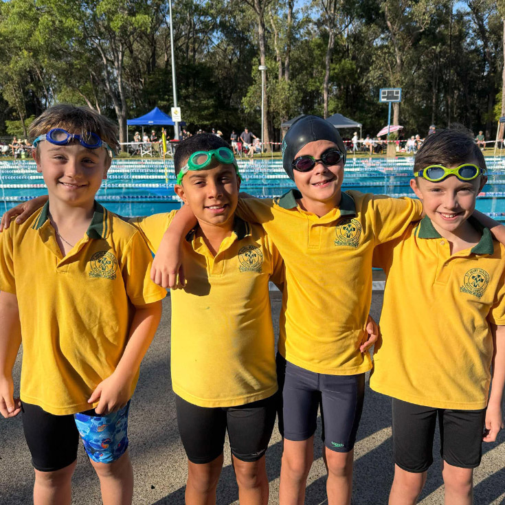 Students smiling at the pool during a swimming carnival at St Mary MacKillop Primary School South Penrith