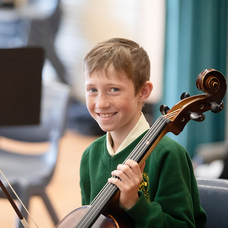 Student learning to play the cello in the classroom at St Mary MacKillop Primary School South Penrith